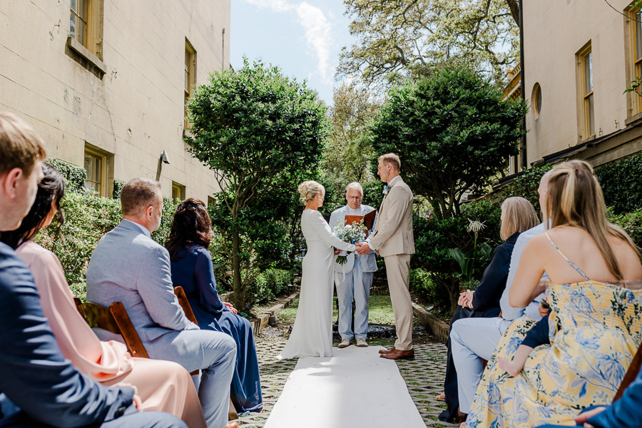 a man and woman holding hands and standing on a path with people sitting in chairs